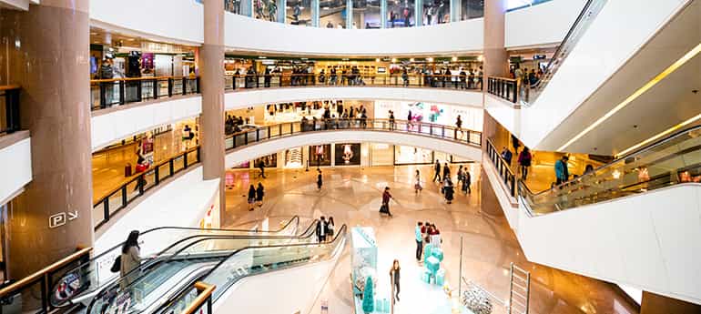 photo of a multistory shopping mall atrium with escalators and shoppers moving to and fro